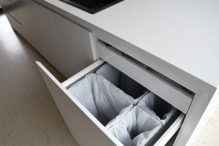 Integrated pull-out bins in kitchen room reveal