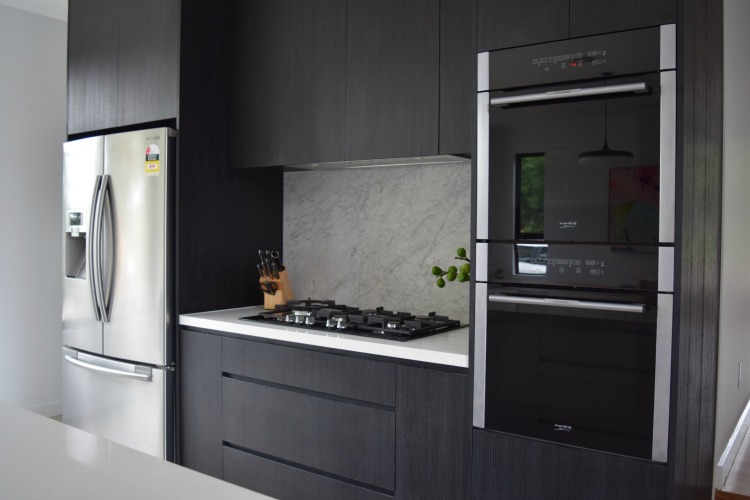Ovens and black joinery in kitchen room reveal