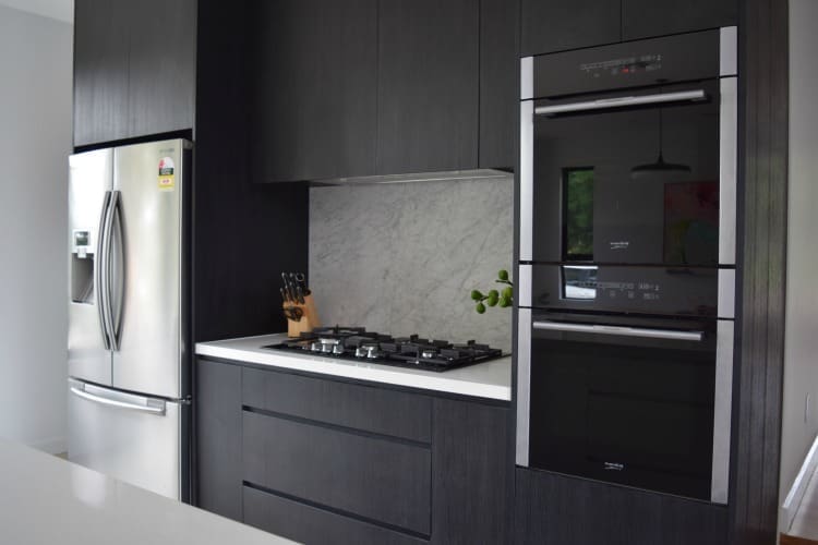 Ovens and black joinery in kitchen room reveal