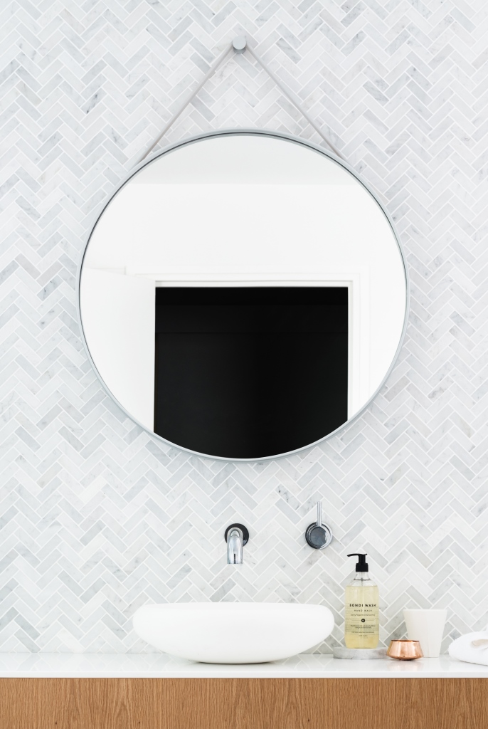 Round mirror against marble tile wall