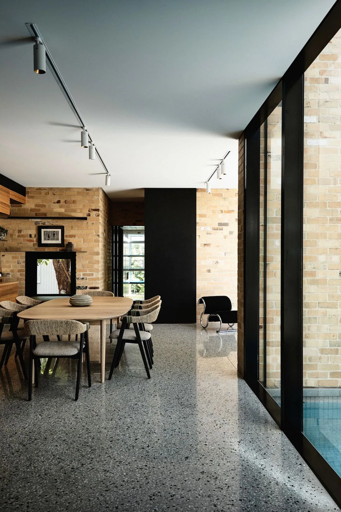 Yellow brick, concrete floors and black framed doors in living dining kitchen space