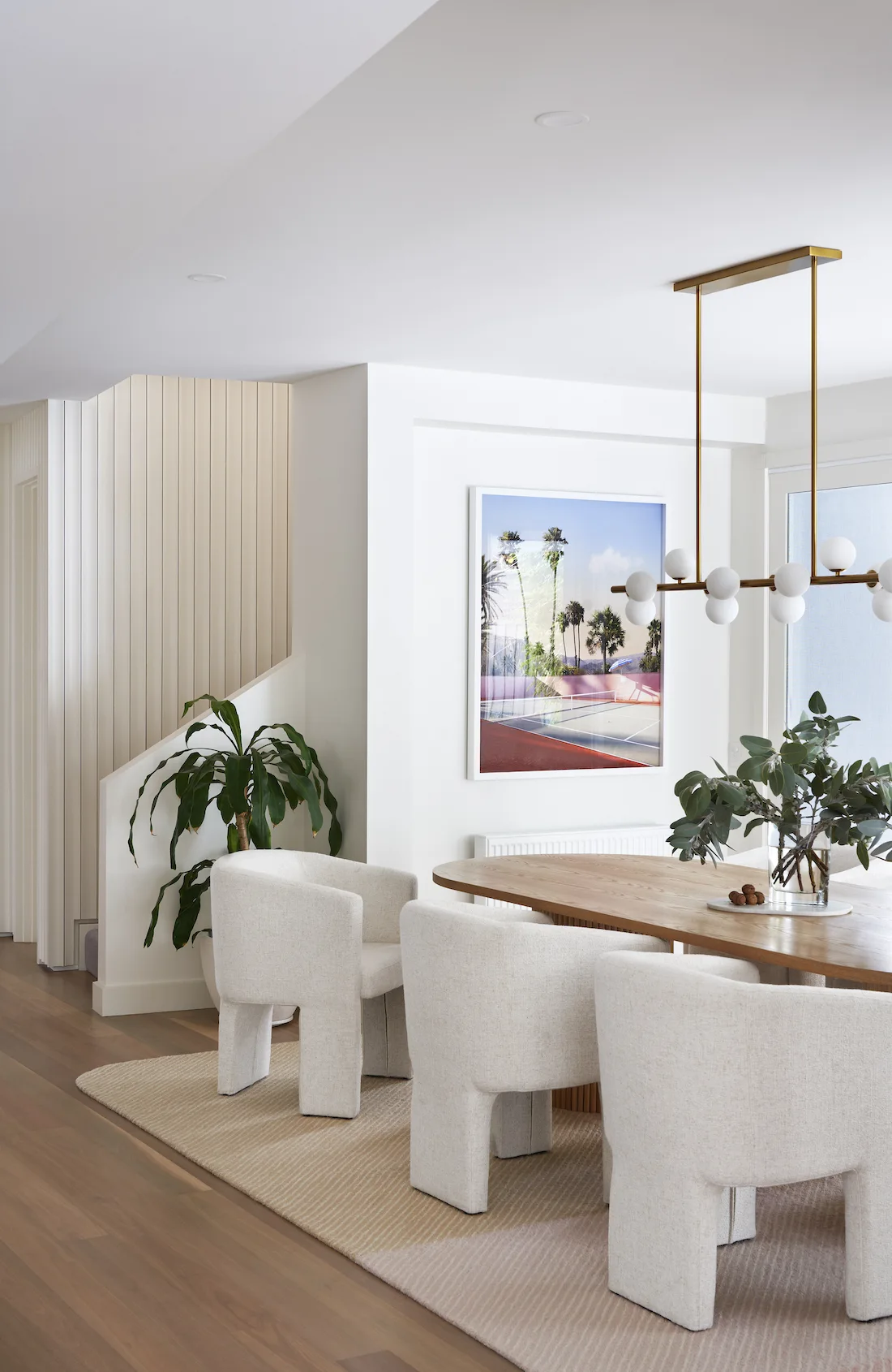 White curved dining chairs and statement pendant