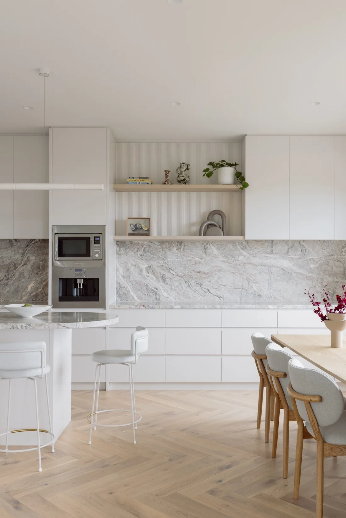 White and marble kitchen with curved island and herringbone flooring