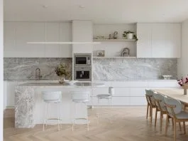 White and marble kitchen with curved island and herringbone flooring