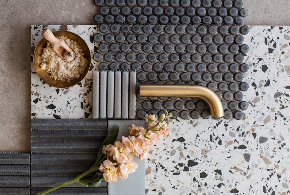 Tapware and tile flatlay featuring terrazzo tile, glazed penny round tiles, kit Kat finger tiles and stone mosaics