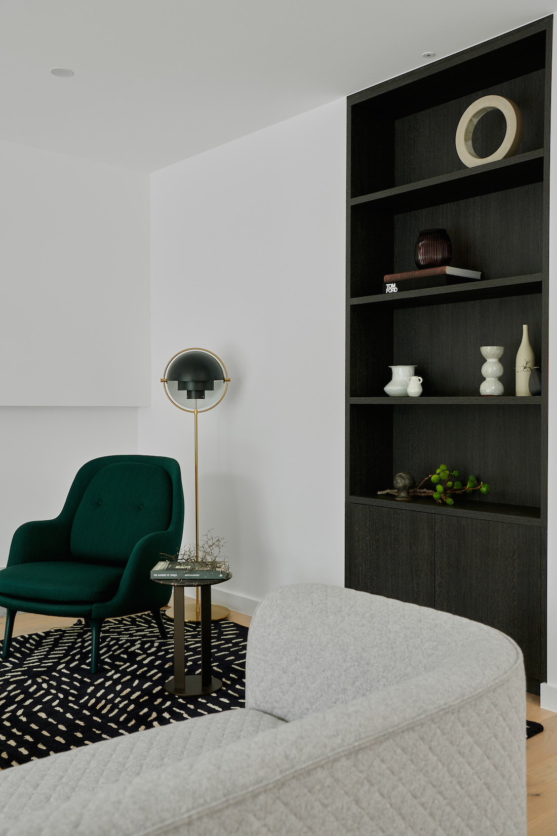 Lounge room with green velvet chair and dark veneer bookcase