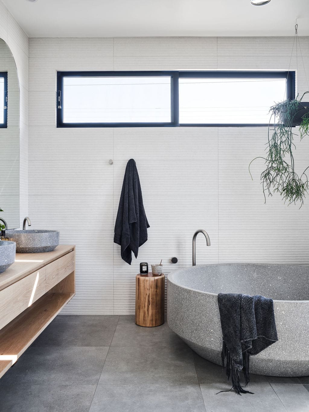 Grey round concrete tub in white and grey bathroom