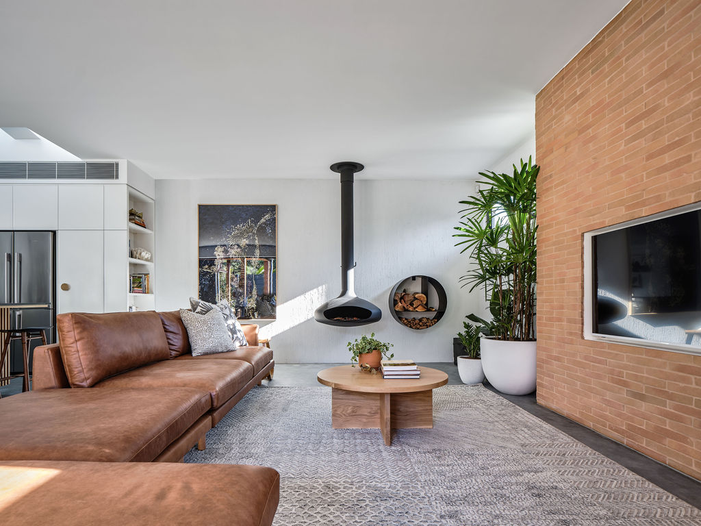 Tan leather lounge with floating fireplace and brick wall
