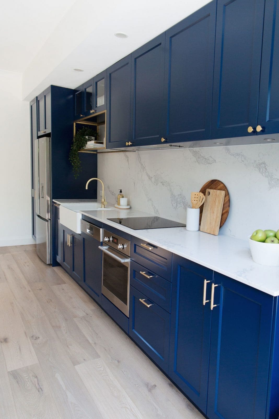 Navy blue kitchen with luxe brass accents and marble look benchtop