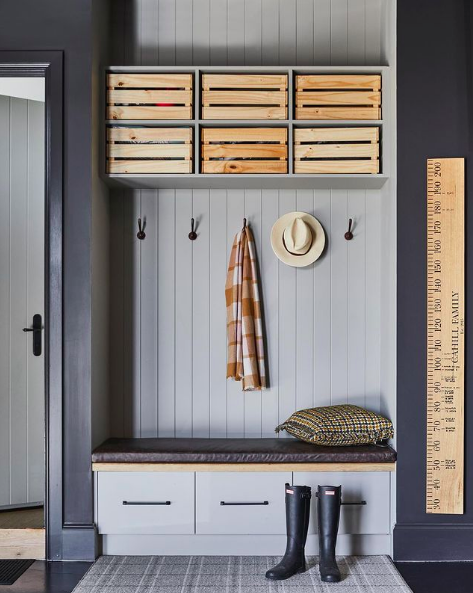 Grey mudroom with wooden boxes for storage in garage and wooden height chart