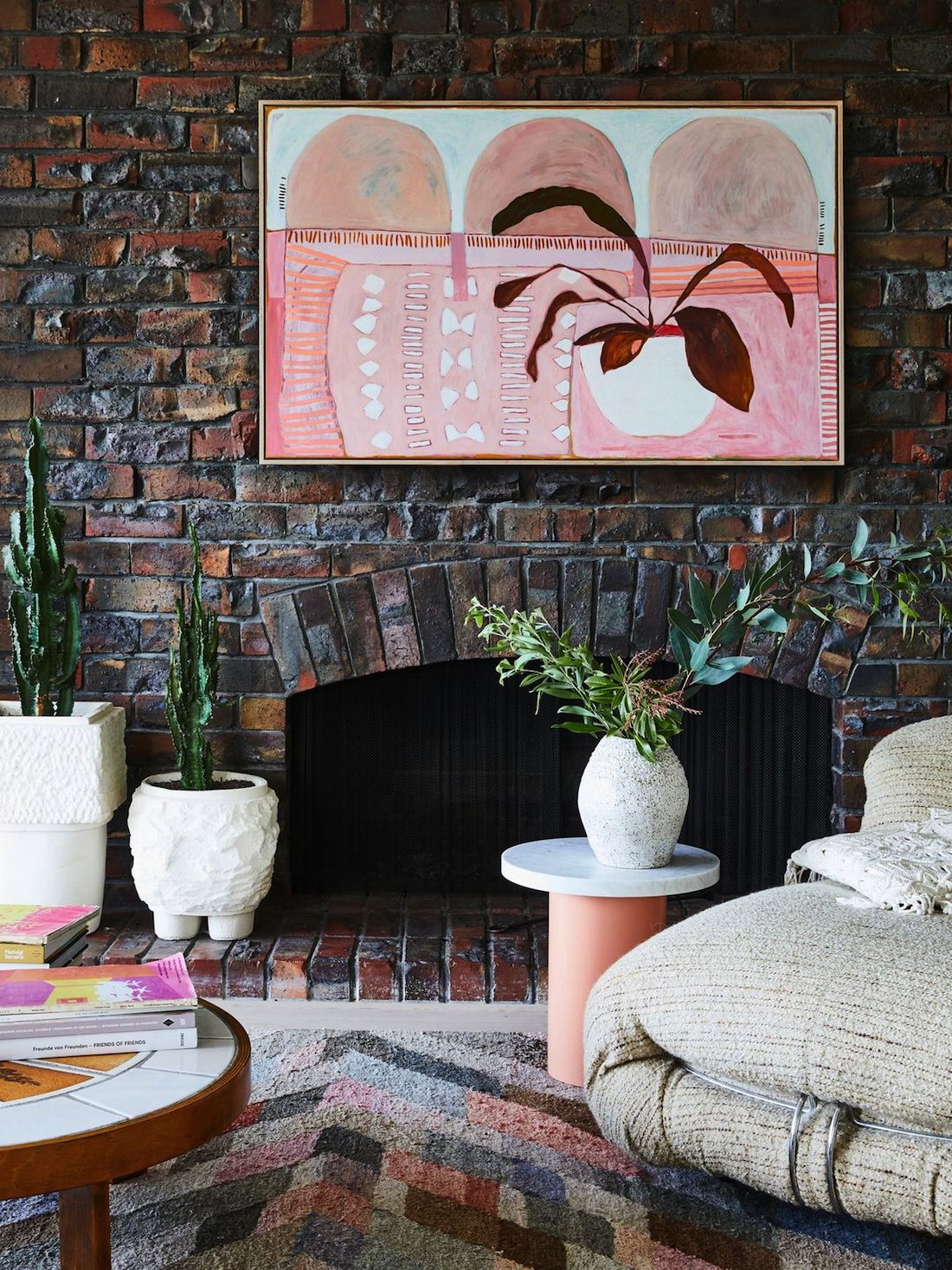 Pink artwork on brick fireplace with ceramic vase