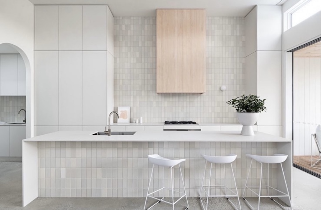 Kitchen with a subway tile splashback to the ceiling and subway island