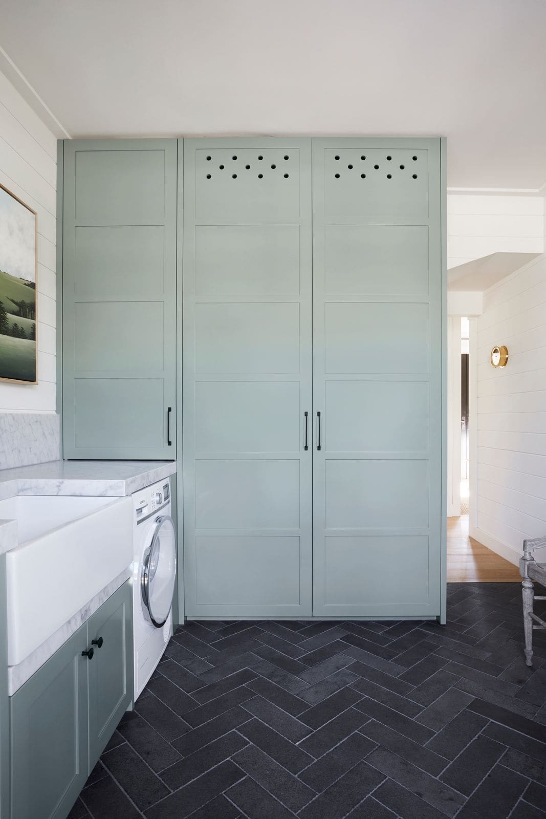 Green cabinetry in sage green and marble laundry