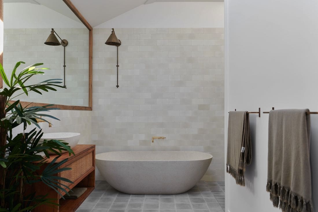 Bathroom with freestanding bath and brass wall sconce