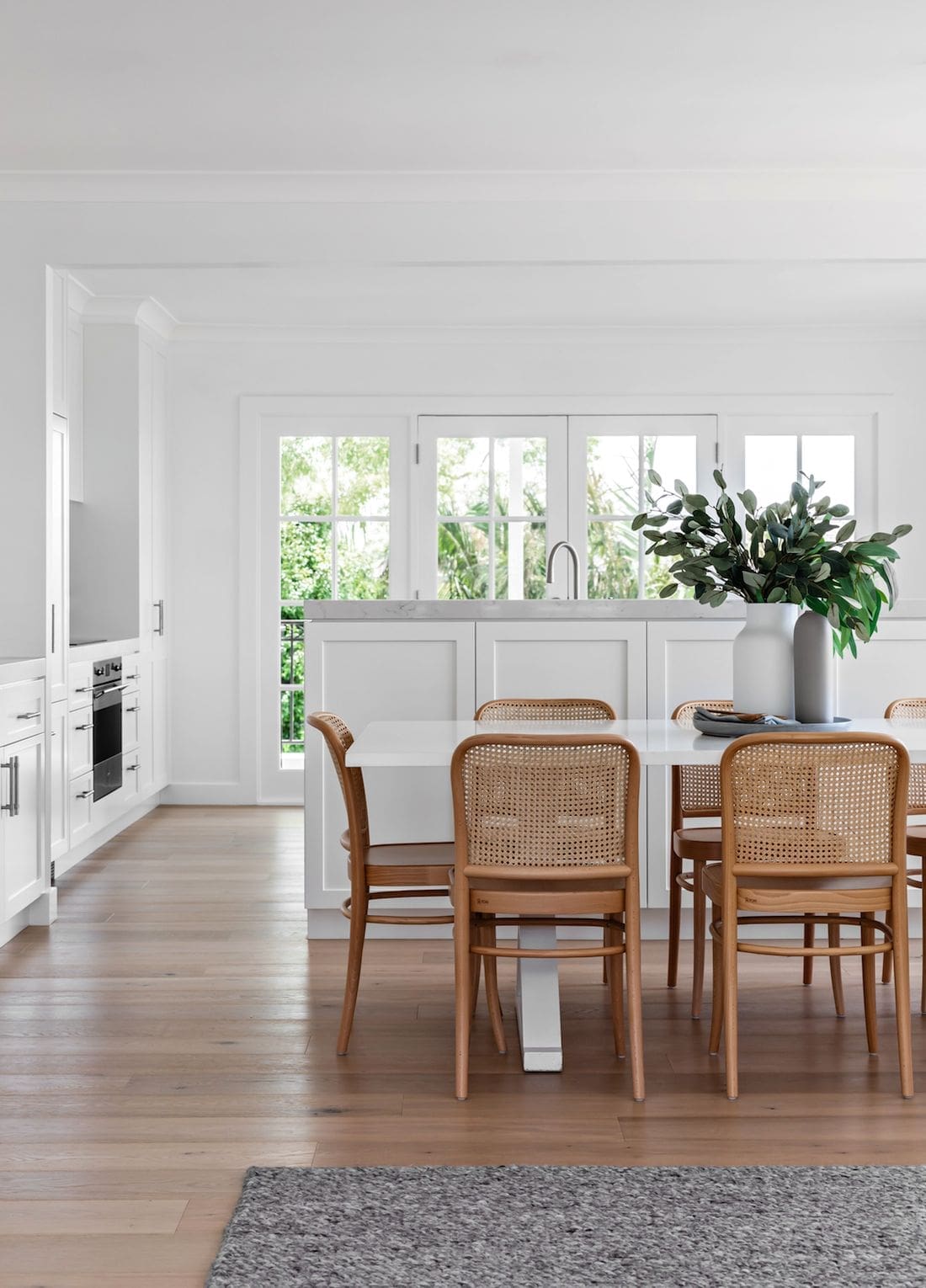 White kitchen with timber and rattan dining chairs