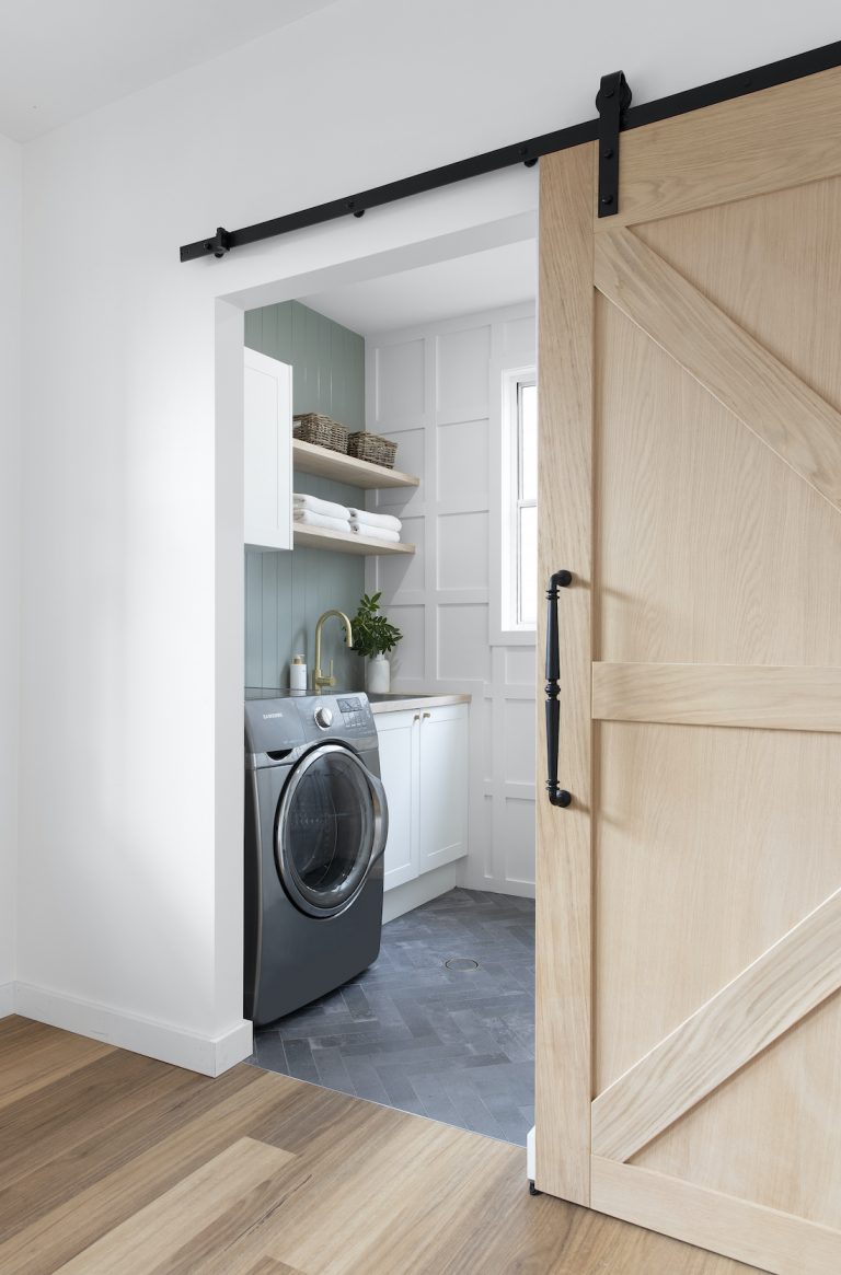 Laundry with panelling, green wall and sliding barn door