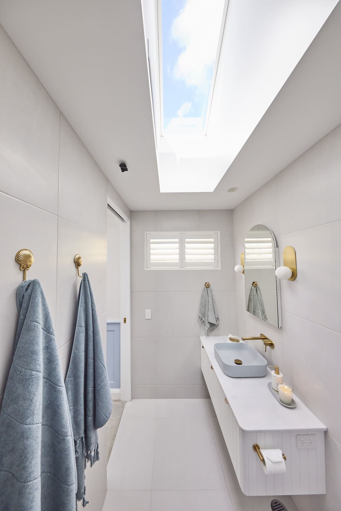 Skylight in narrow blue and white bathroom