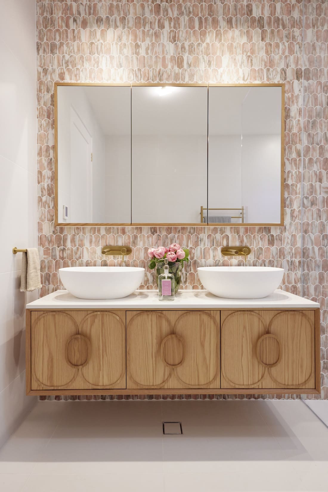 Floating timber vanity in pink tiled bathroom