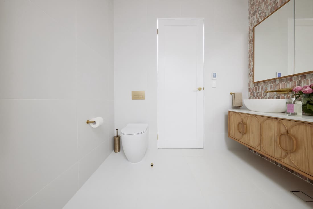 Toilet tucked behind door in guest ensuite bathroom