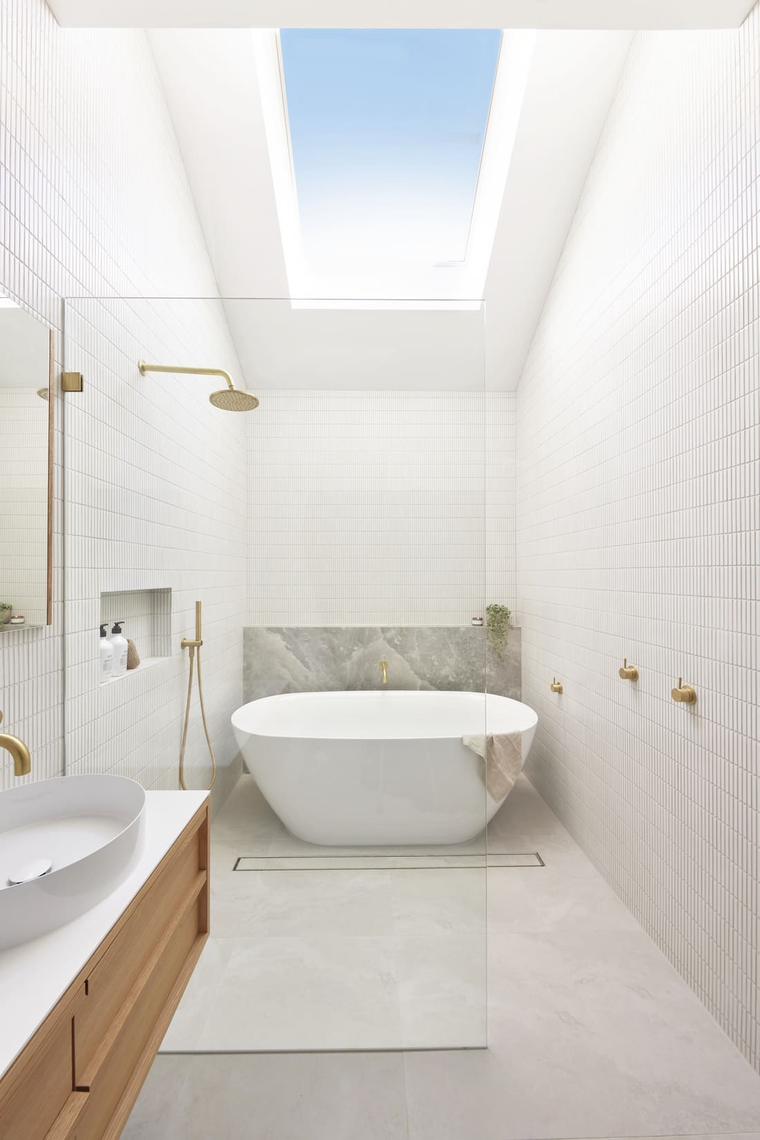 White bathroom with skylight and freestanding curved bath