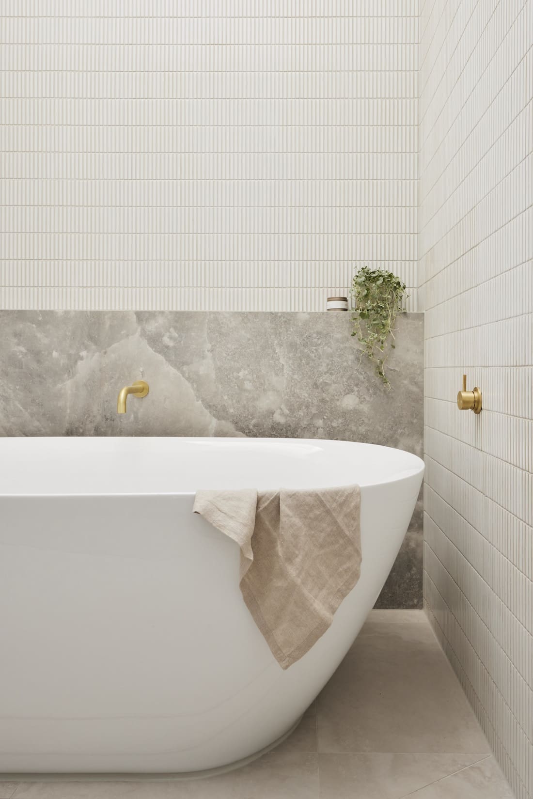 Curved bath with marble look tiles and white kit kat tiles