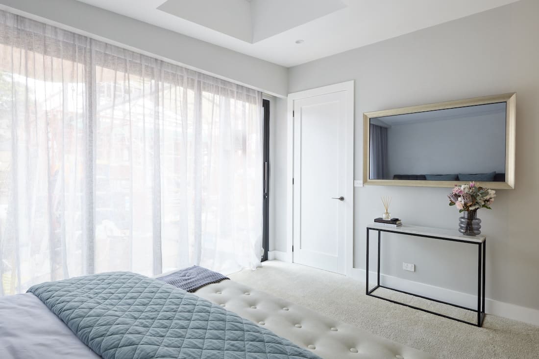 Black framed side table and sheer curtains in master bedroom