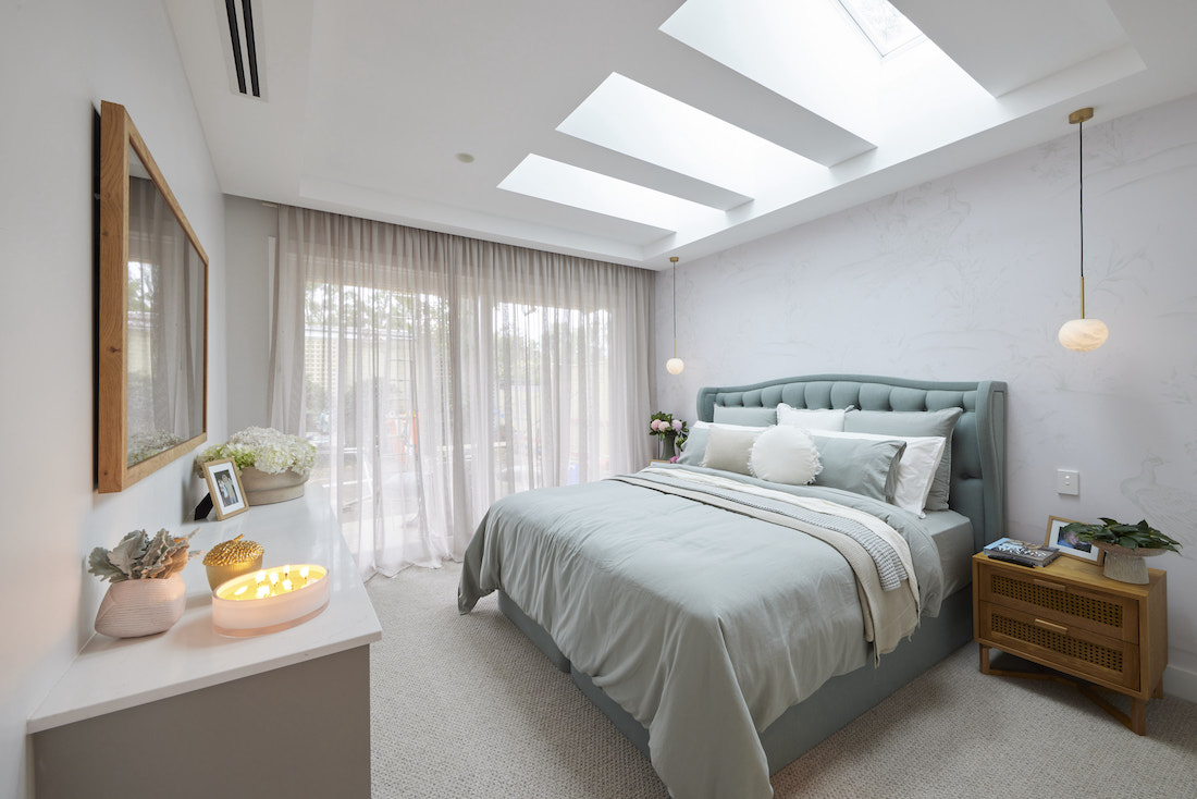 Master bedroom with green headboard and skylights