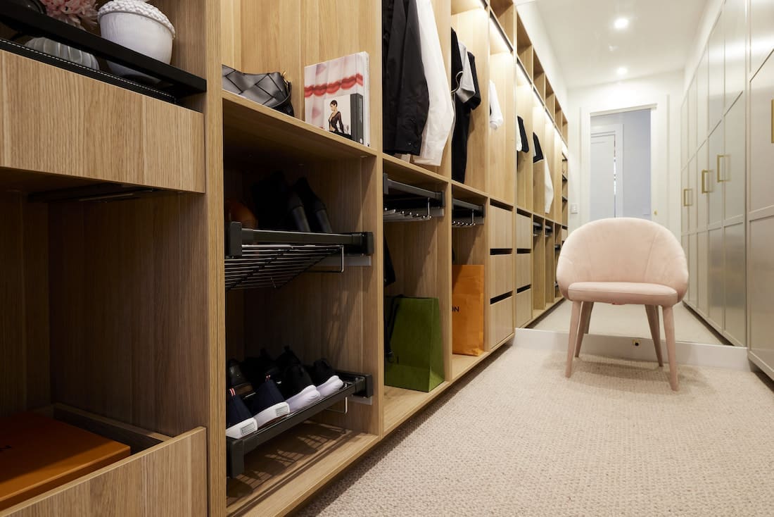 walk in wardrobe with timber open shelving and pink velvet chair