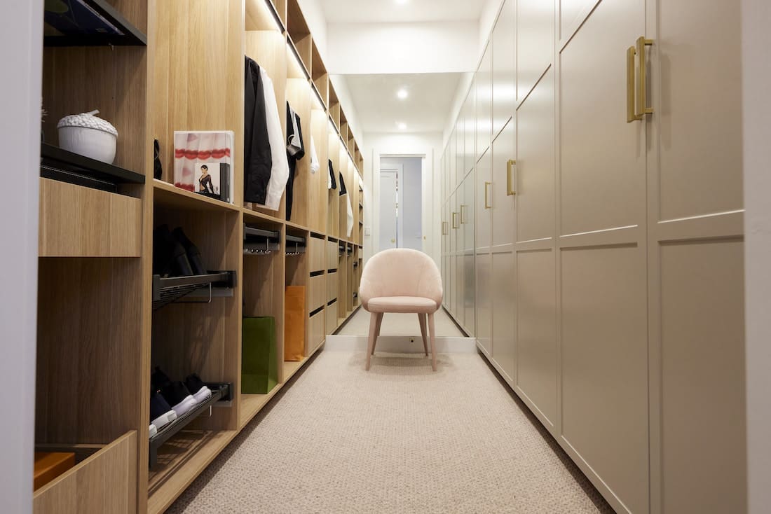 walk in wardrobe with timber open shelving and pink velvet chair