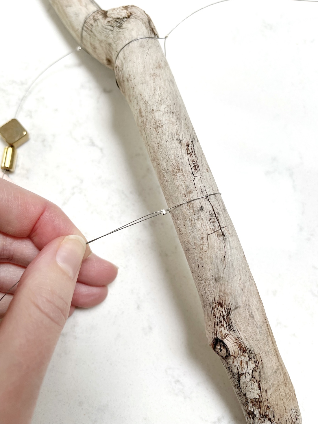 Use beading wire to hang the driftwood wall art