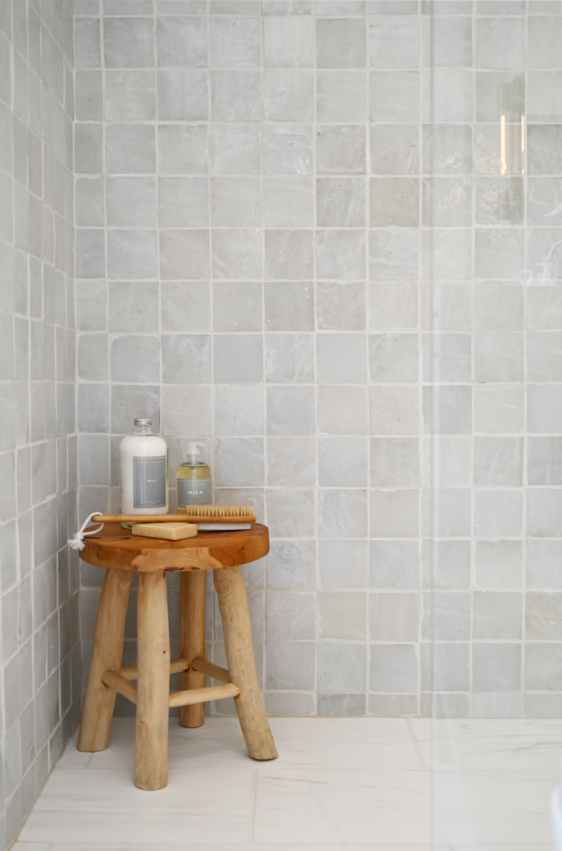 Gray square tiles in bathroom with wooden stool