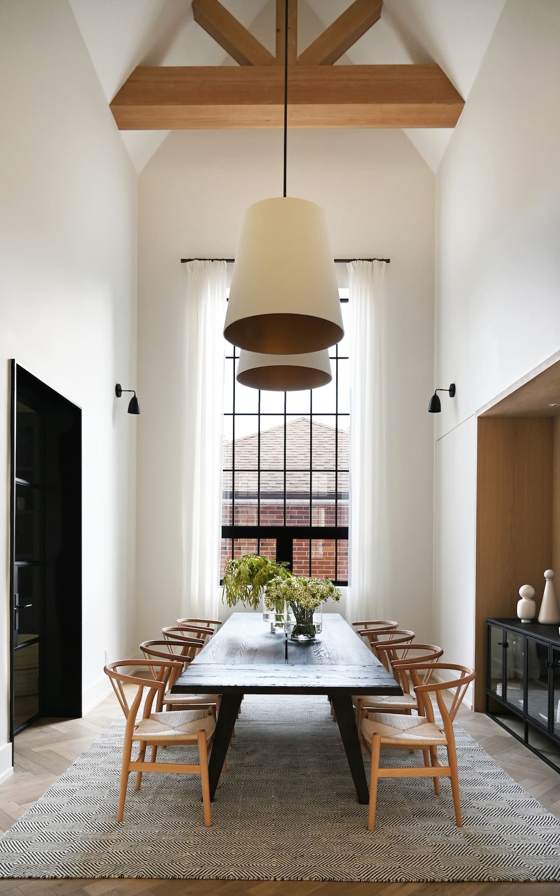 Dining table with oversized pendant lights and floor to ceiling window