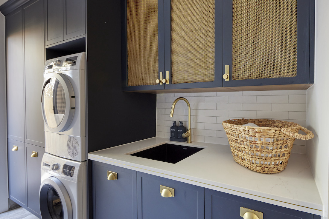Laundry cabinetry in navy and brass insets