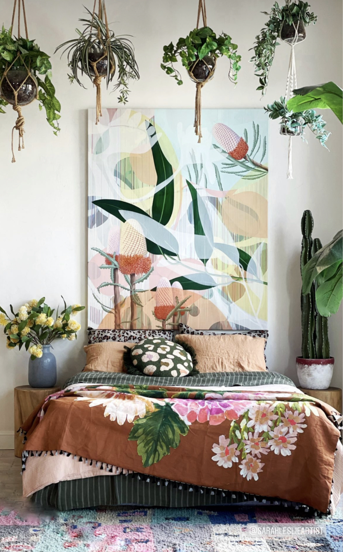 Sarah Leslie artwork above bed with hanging plants