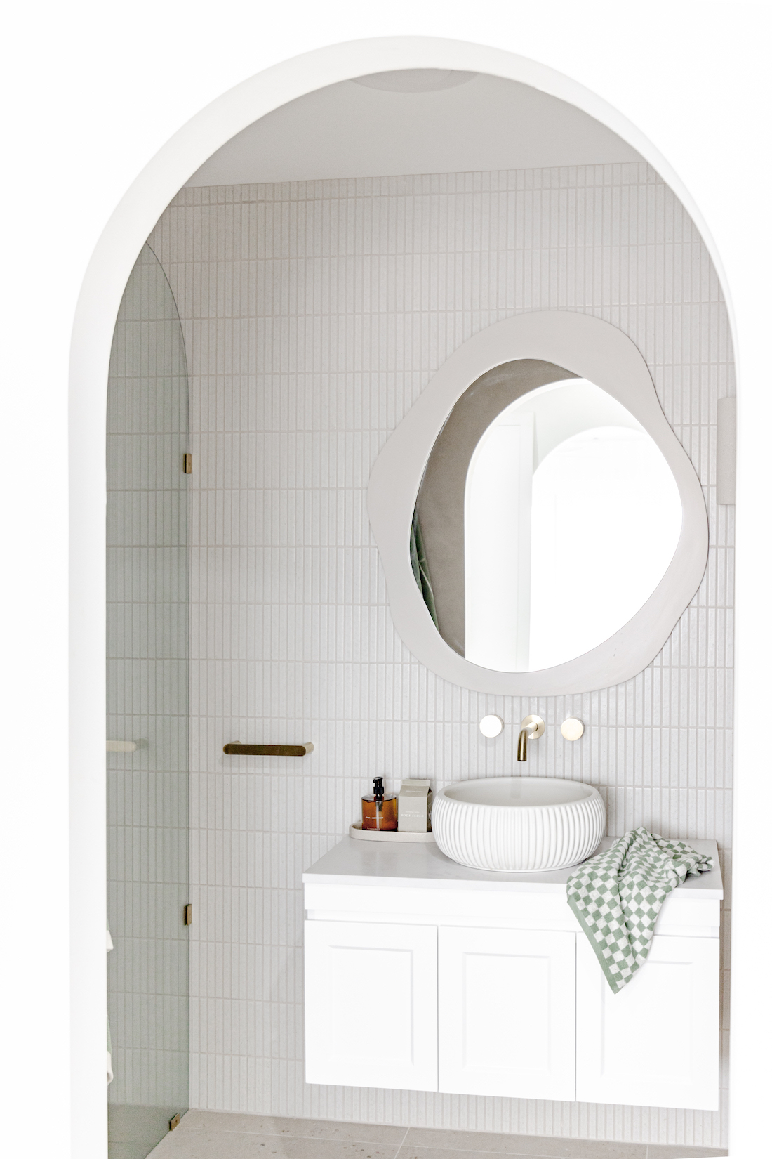 Curved doorway to white kitkat tile bathroom