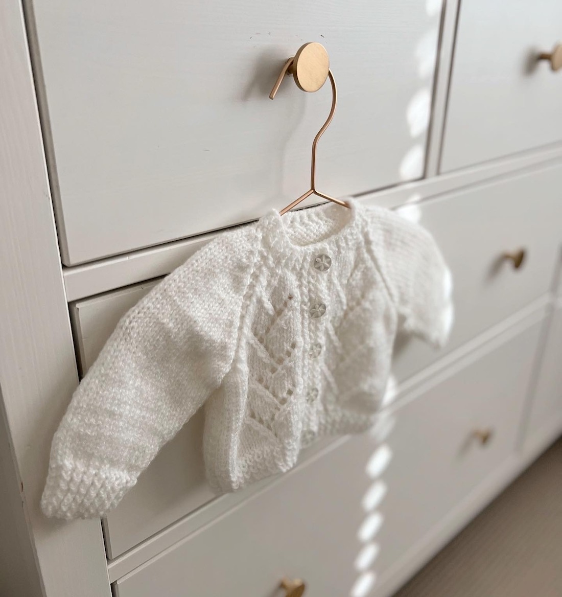 Handmade baby jumper hanging on chest of drawers