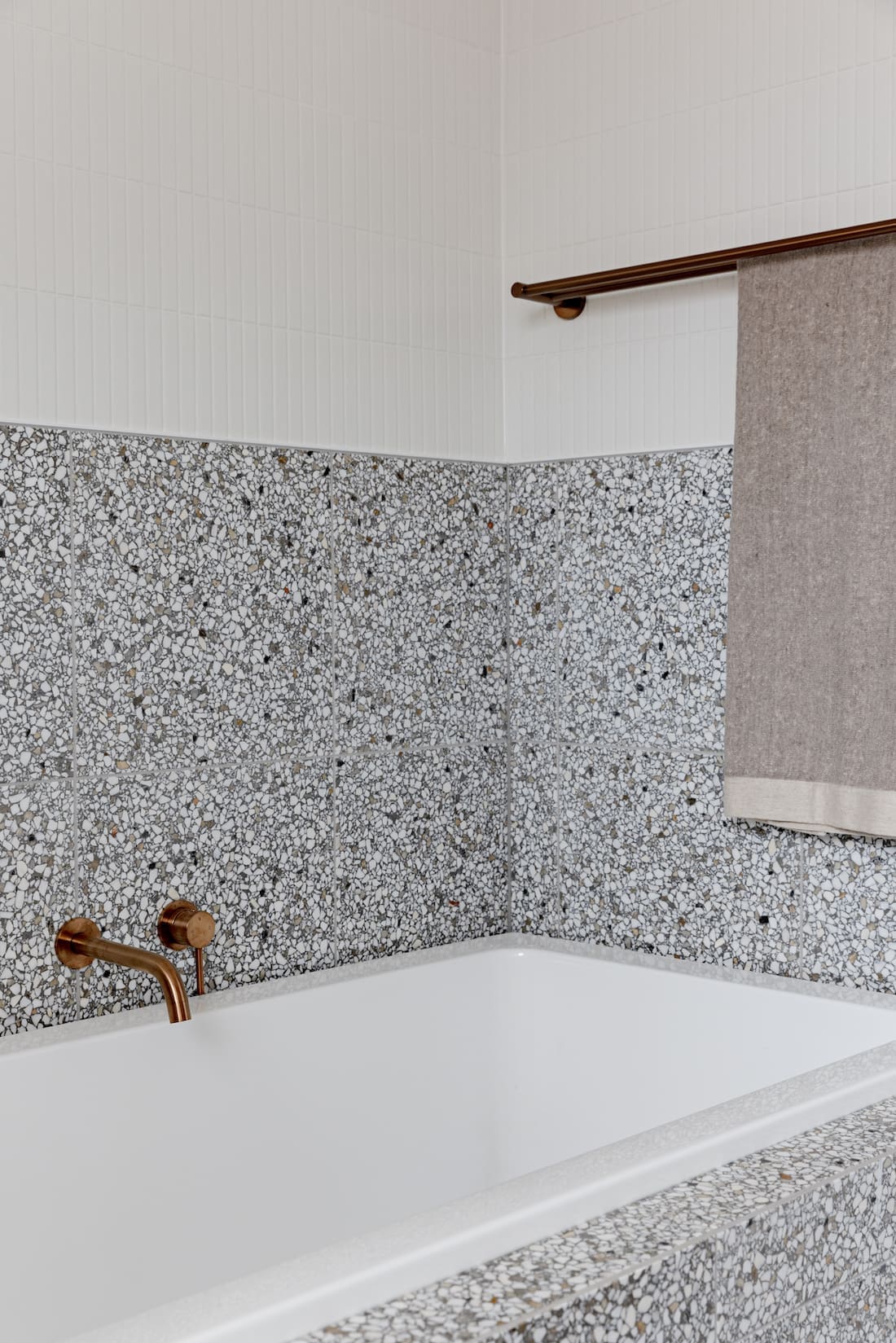 Grey terrazzo half-height wall above bath