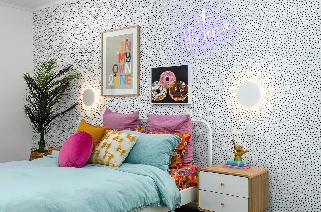 Spotty wallpaper and colourful bedding in teen bedroom