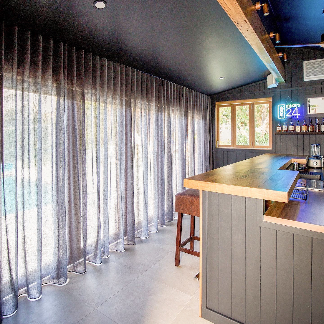 Sheer curtains in man cave with timber bar