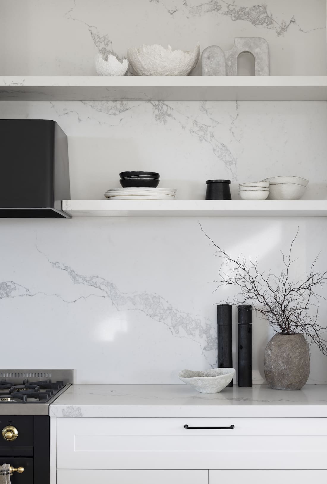 Veined stone splash back in white and black kitchen