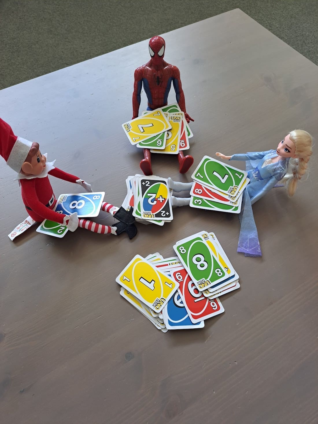 Elf on the shelf playing uno with Elsa and Spiderman