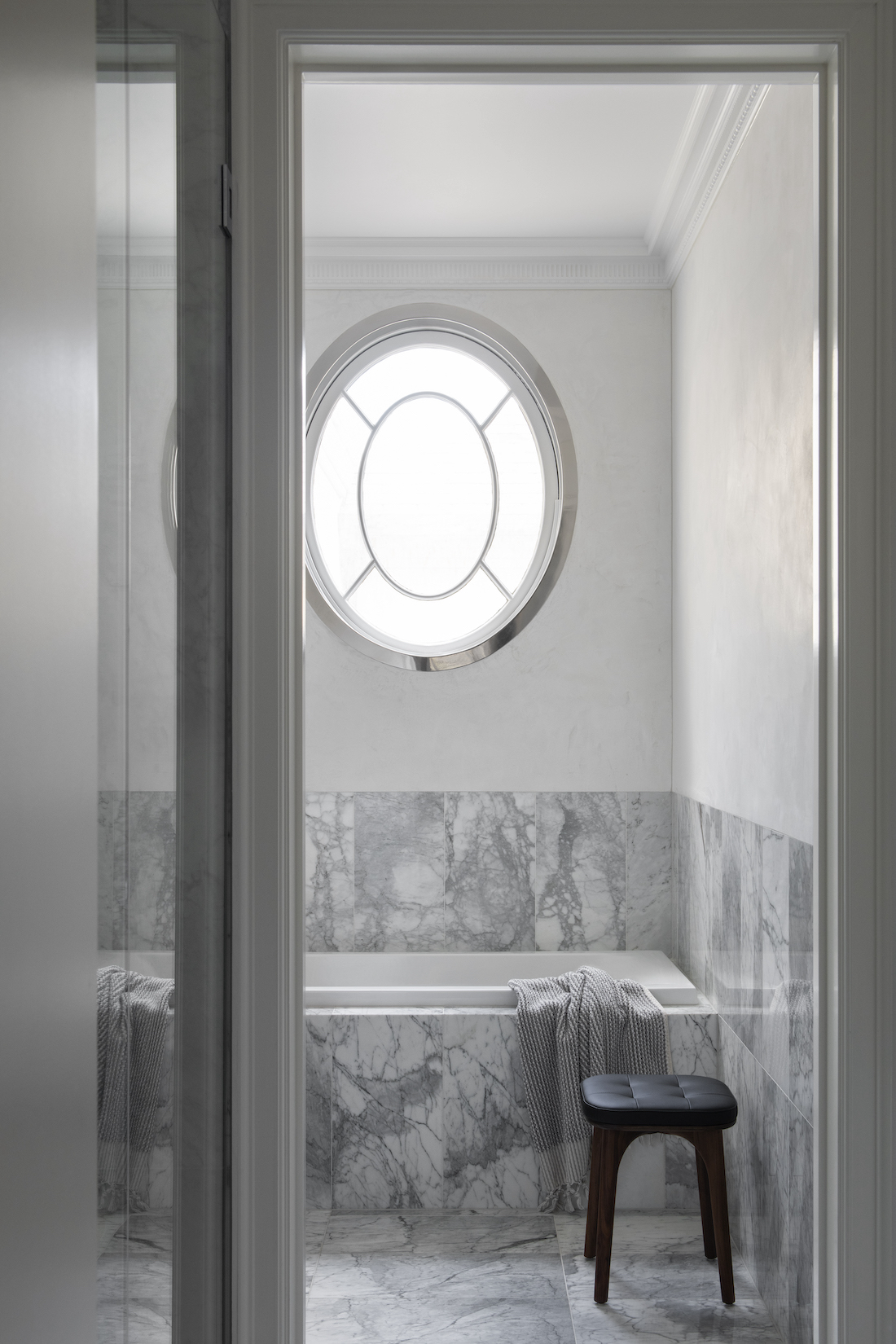 Transcontinental Residence marble bathroom with oval window