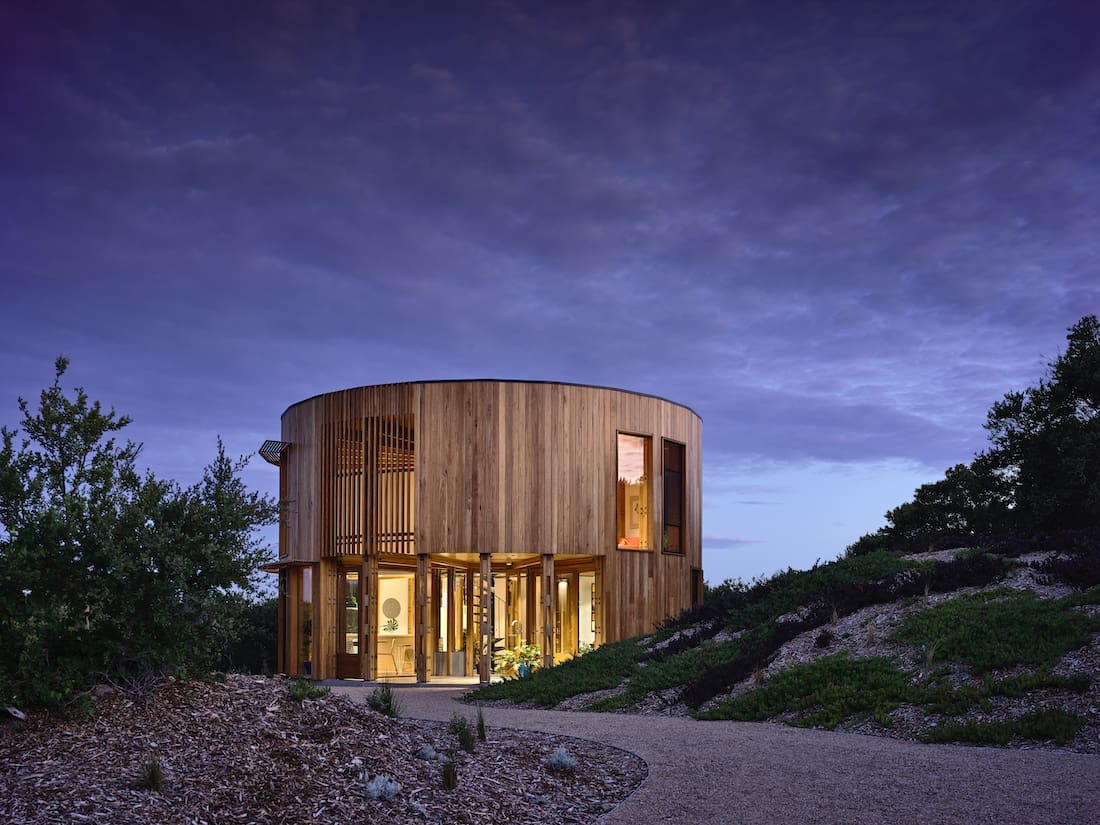 Round timber beach house at night