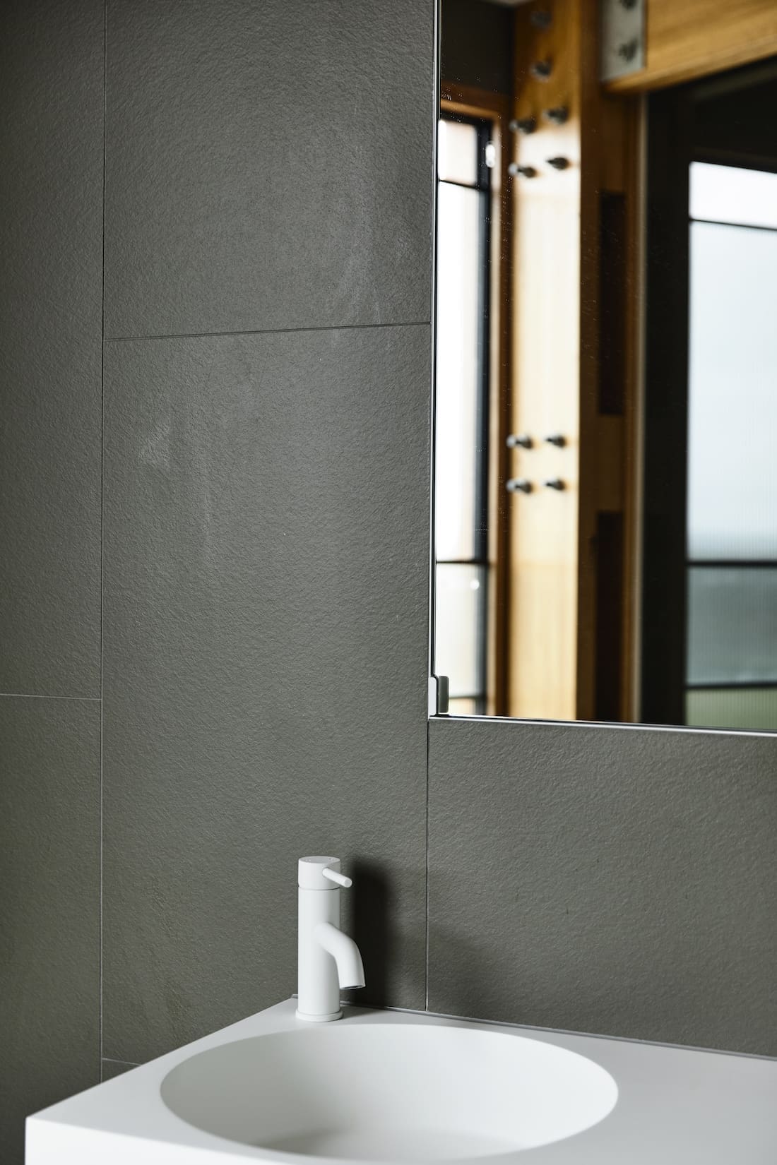 Grey wall tiles with white tap and vanity in bathroom