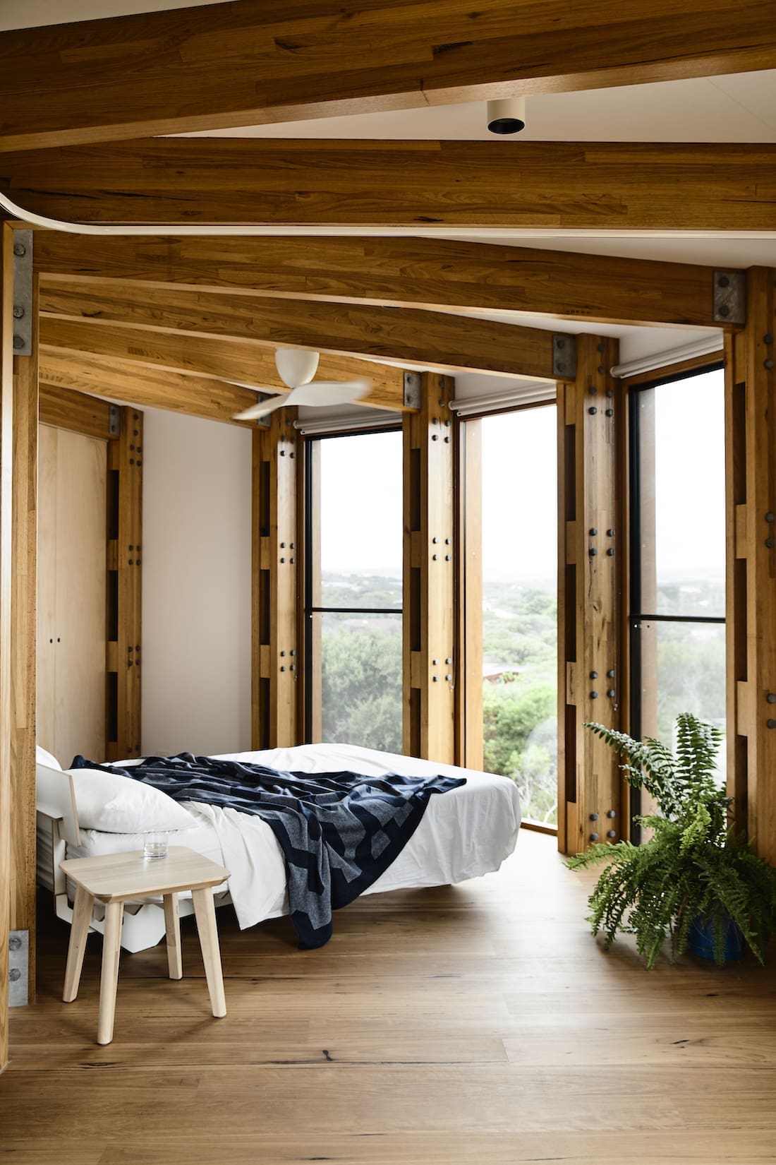 Minimalist bedroom with white fan and exposed timber beams