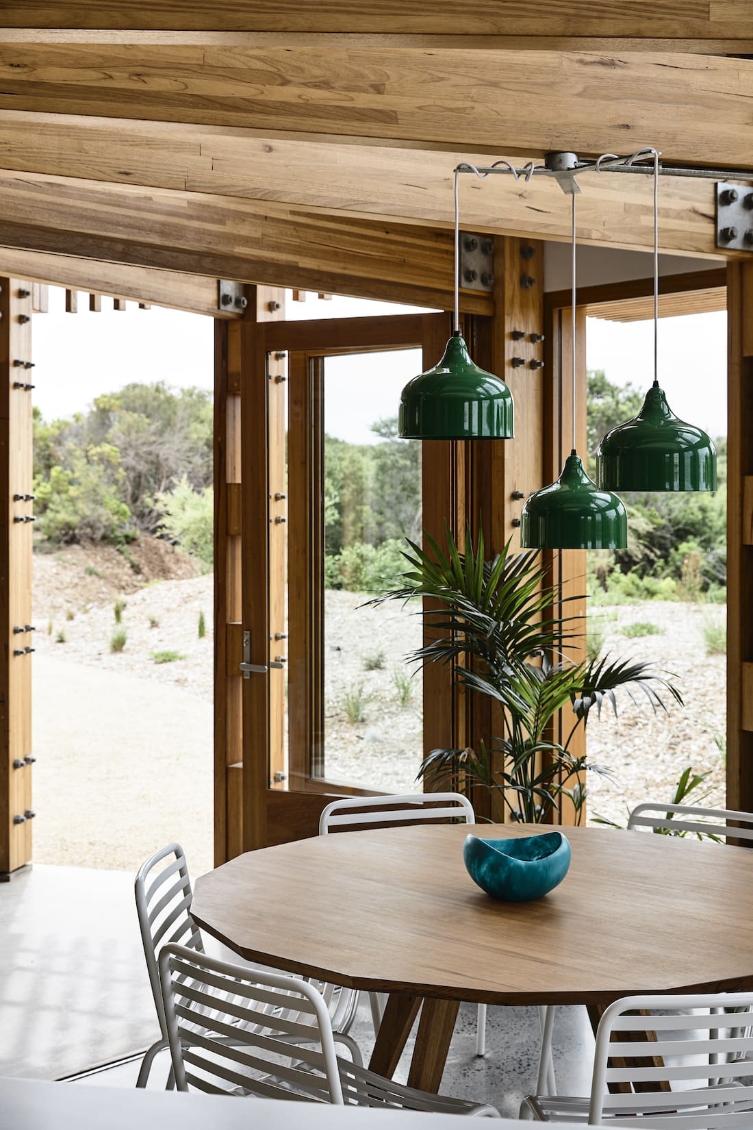 Green metal pendant lights over dining table