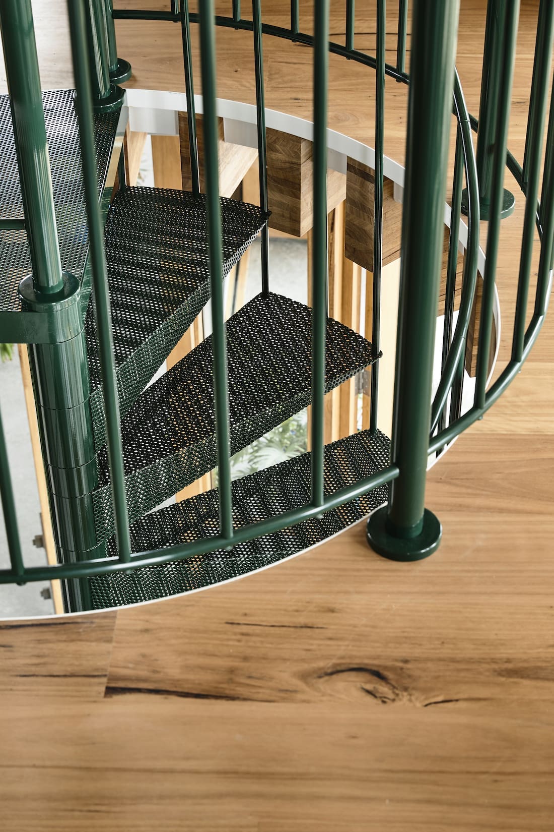 Green metal spiral staircase and timber floors