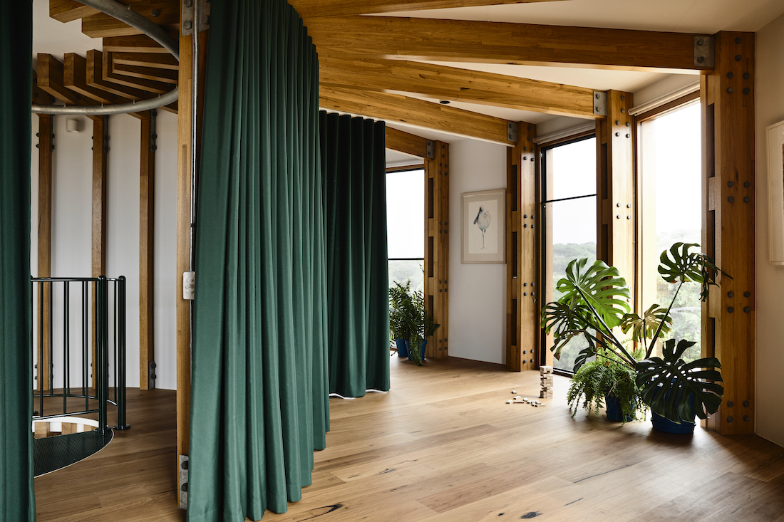 Timber beams and flooring in round house with green curtains