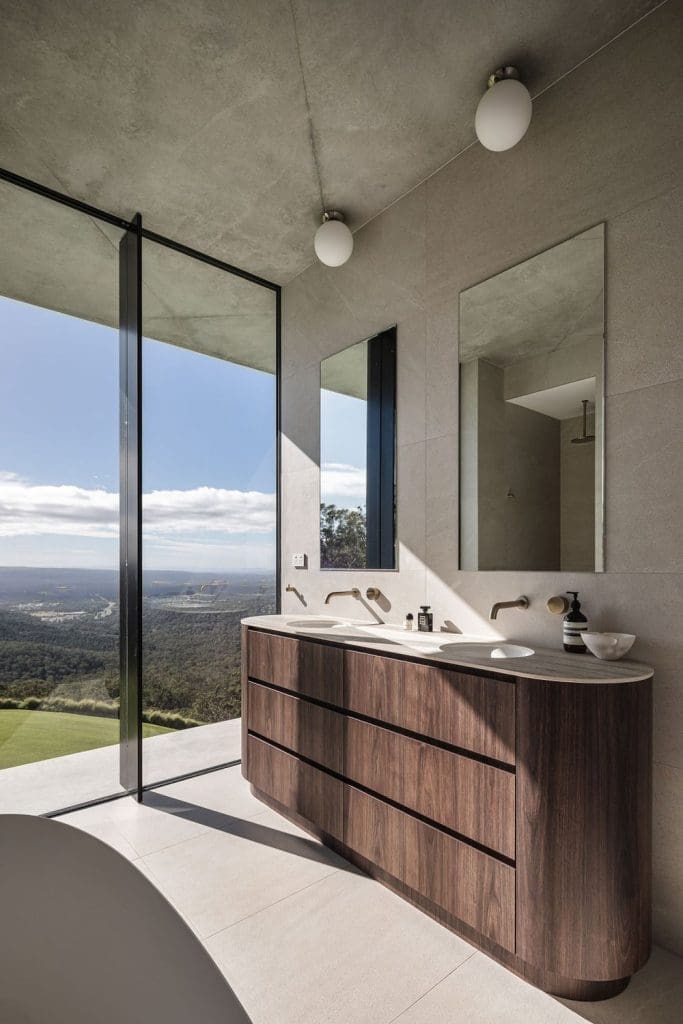 Bathroom with walnut curved vanity and glass wall with expansive views