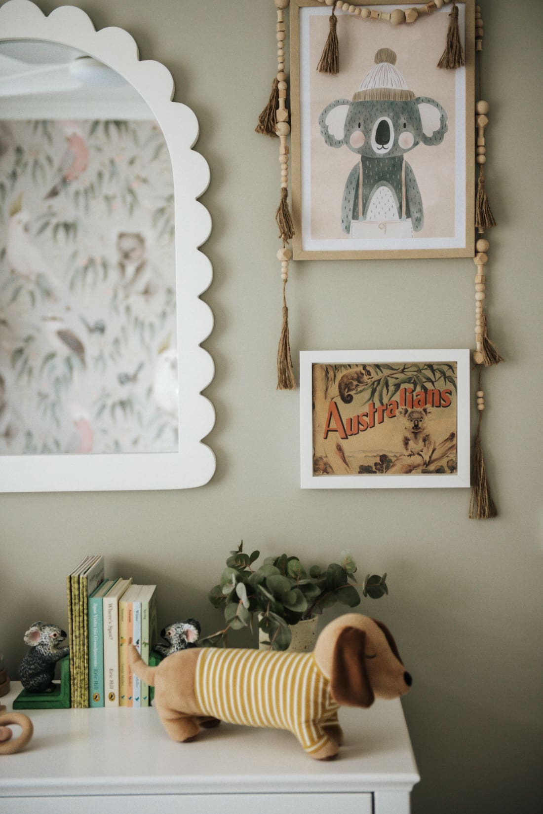 Artwork and scalloped mirror in baby nursery